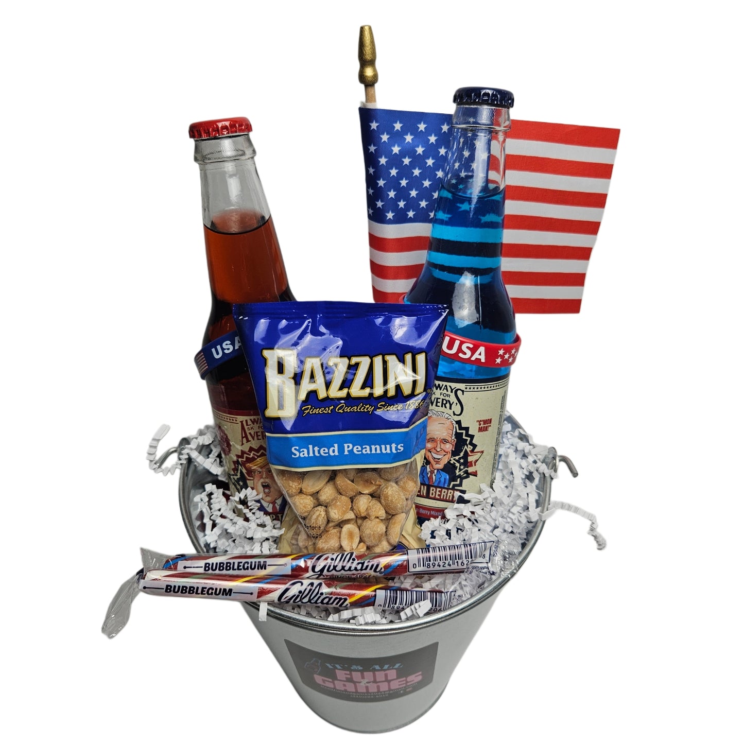 Image of the bucket with an American flag, two bottles of soda, Bazzini peanuts, 2 Gilliam candy sticks and two rubber bracelets that say USA.